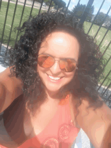 a woman with curly hair is wearing sunglasses and a pink top