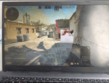 a laptop screen shows a video game with a red arrow pointing to the 5x30 preview