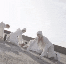 a group of people in white clothes are kneeling on the ground .