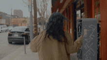 a woman is walking down a sidewalk next to a vending machine that says ' ice cream ' on it