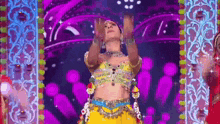 a woman in a yellow dress is dancing on a stage in front of a purple background .