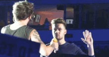 two men are standing next to each other on a stage and one of them is feeding the other something .