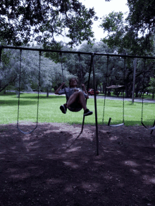 a young girl swings on a swing set in a park