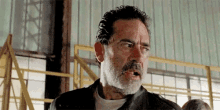 a man with a beard and a leather jacket is making a funny face in a room .