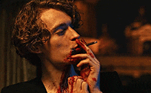 a bloody man is smoking a cigarette with blood on his face