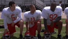 a group of football players are kneeling on the field and one of them has the number 92 on his jersey