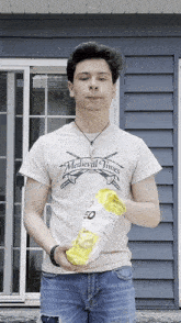 a young man wearing a medieval times shirt holds a bag of chips
