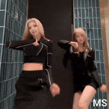 two women are dancing in front of a wall with the letters ms on the bottom