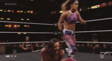 a woman is wrestling another woman in a ring on a tv show .