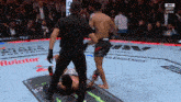 a fighter is laying on the ground while a referee stands over him