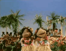 two stuffed animals wearing hawaiian outfits are dancing in front of palm trees