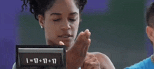 a woman is holding her hand up in front of a clock that says j = 301-103 .