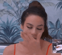a woman in a red top is covering her mouth with her hand