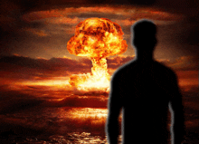 a silhouette of a man stands in front of an explosion over the ocean