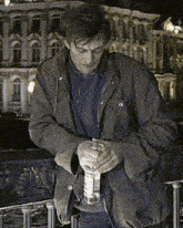a man in a brown jacket is holding a bottle of water