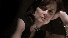 a close up of a woman 's face with a silver buckle around her neck