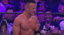 a man in a wrestling ring holds up a belt that says aew on it