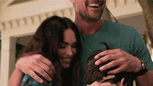 a man and a woman are hugging a child while a man scratches his head .