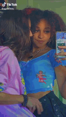 a woman is taking a selfie in front of a mirror while wearing a pink hoodie and a blue crop top .