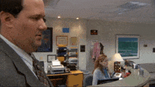 a man in a suit stands in front of a teamwork poster
