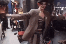 a drag queen is dancing in a room with her arms outstretched .