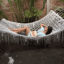 a woman laying in a hammock with a book