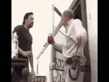 two men are standing next to each other in front of a trailer .