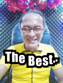 a man wearing glasses and a yellow shirt is smiling with the words " the best " above him