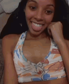 a woman wearing a floral sports bra is sticking her tongue out