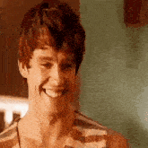 a young man in a striped tank top is smiling and looking at the camera .