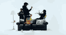 a group of people are dancing on a couch in a room .