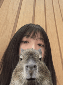 a woman holds a squirrel in front of her face