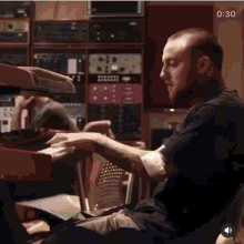 a man with a prosthetic arm is playing a keyboard in a recording studio