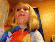 a young girl with blonde hair is wearing a colorful shirt