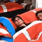 a man and a woman are laying in a bed with red , white and blue blankets .
