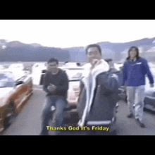 a group of people are standing in a parking lot and one of them is saying thanks god it 's friday