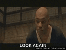 a man in a kimono is standing in a dark room with the words look again below him