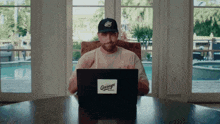a man is sitting at a table with a laptop that says garage on it