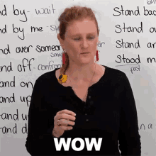 a woman is standing in front of a white board with the word wow on it