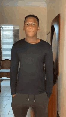 a young man in a black shirt is standing in a hallway