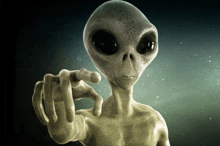a grey alien pointing at the camera with his finger