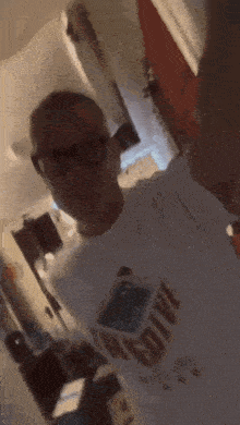 a man wearing glasses and a white shirt with the word diva on it is taking a selfie