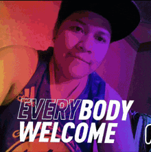 a woman wearing a hat and a tank top with the words everybody welcome