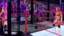 a woman is standing in a wrestling ring talking to another woman .