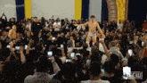 a wrestler stands in front of a crowd with #bloodsport9 written on the screen
