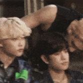 a group of young men are sitting next to each other and one of them has his hand on the other 's head .