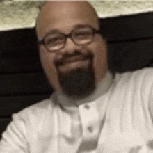 a man with a beard and glasses is taking a selfie with his phone .