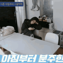 a woman sits at a table looking at her phone with a sign above her that says ' oi ' on it