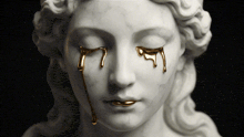 a statue of a woman 's face with gold tears coming out of her eyes