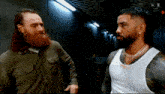 two men are standing next to each other in a room and talking .